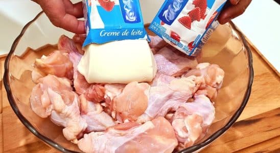 Frango com creme de leite sendo preparado, com pedaços de frango crus em uma tigela de vidro, e uma pessoa adicionando duas caixas de creme de leite.