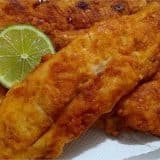 Peixe sequinho e crocante, empanado e frito, servido com rodelas de limão, em uma apresentação apetitosa e dourada.