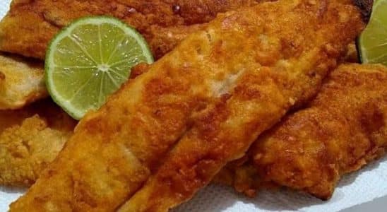 Peixe sequinho e crocante, empanado e frito, servido com rodelas de limão, em uma apresentação apetitosa e dourada.