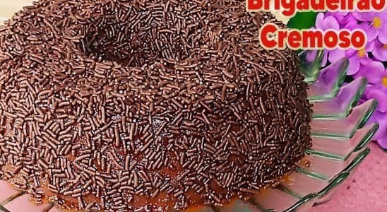 Brigadeirão cremoso, coberto com granulado de chocolate, servido em um prato de vidro.