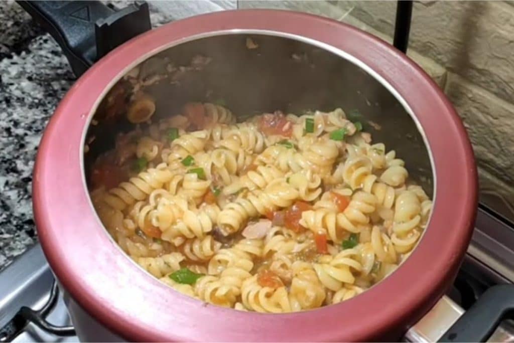 Macarrão com atum sendo preparado em uma panela de pressão vermelha.