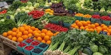 Bancada de feira com frutas e vegetais frescos da estação, coloridos e abundantes.