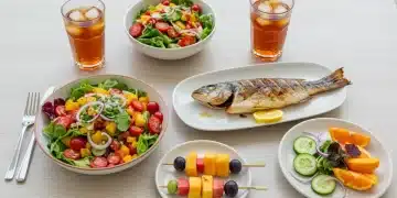 Mesa com pratos rápidos de verão, incluindo salada colorida, peixe grelhado e frutas frescas, em um ambiente iluminado de verão.