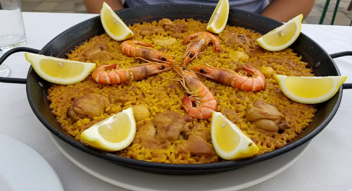 Paella valenciana auténtica con mariscos y pollo, servida en una paellera tradicional.