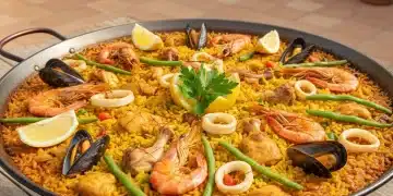 Paella valenciana autêntica com arroz dourado e frutos do mar frescos, servida em uma paellera tradicional.